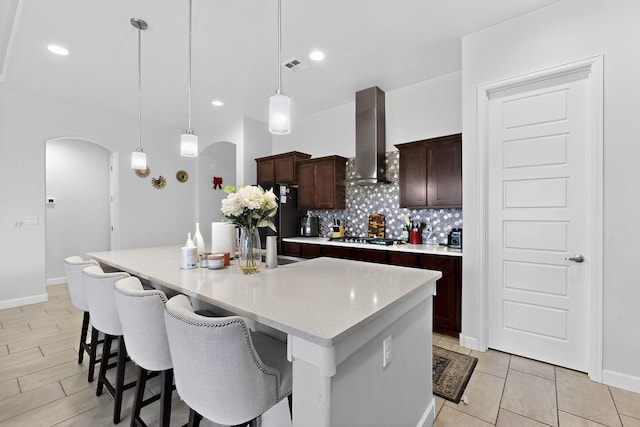 6854 Cleary Loop NE, Rio Rancho, NM 87144 - kitchen featuring wall chimney exhaust hood, arched walkways, light countertops, a kitchen island with sink, and decorative backsplash