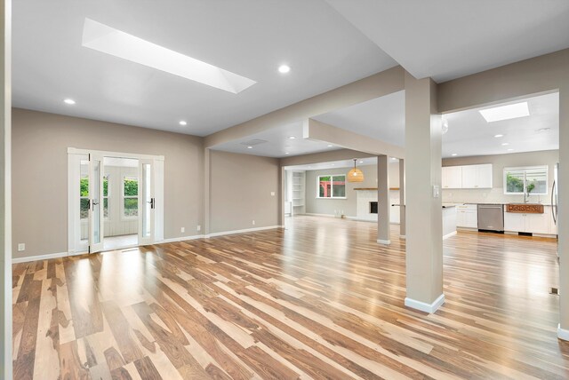 8320 Cherry Hills Dr NE, Albuquerque, NM 87111 - unfurnished living room featuring light wood-style floors, baseboards, a lit fireplace, recessed lighting, and a skylight
