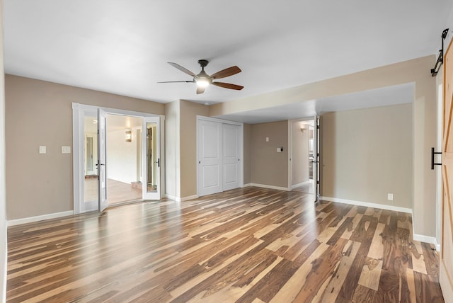 8320 Cherry Hills Dr NE, Albuquerque, NM 87111 - unfurnished living room featuring wood finished floors, ceiling fan, baseboards, and a barn door