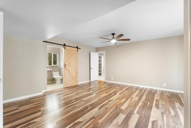 8320 Cherry Hills Dr NE, Albuquerque, NM 87111 - unfurnished bedroom with a barn door, light wood-type flooring, and baseboards