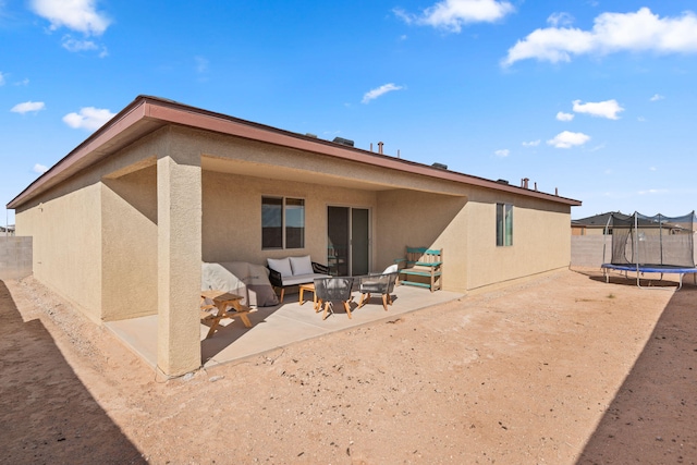 2425 Desi Loop, Belen, NM 87002 - rear view of house featuring a trampoline, stucco siding, an outdoor hangout area, and a patio