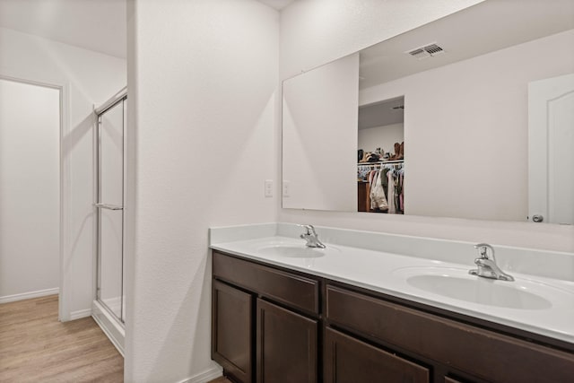 2425 Desi Loop, Belen, NM 87002 - full bath with double vanity, a shower stall, wood finished floors, and a walk in closet