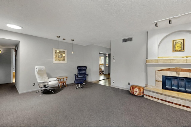 7313 Valley Forge Rd NE, Albuquerque, NM 87109 - sitting room with carpet floors, a tile fireplace, a textured ceiling, rail lighting, and baseboards
