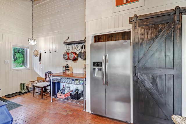 78 Slate Rd, Jemez Springs, NM 87025 - kitchen featuring stainless steel fridge with ice dispenser, a barn door, brick patterned floors, wood walls, and a towering ceiling