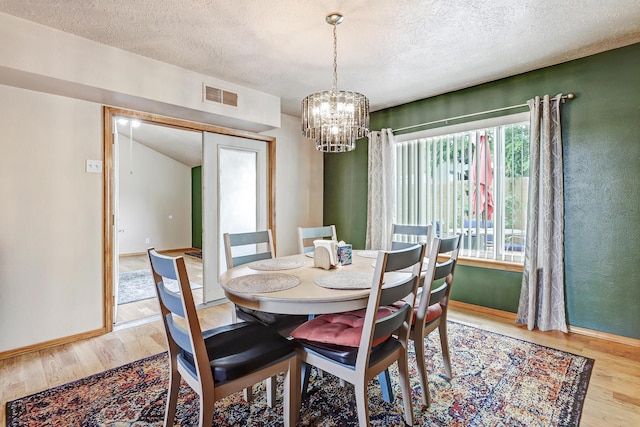589 Diez Y Ocho Ct SE, Rio Rancho, NM 87124 - dining area featuring wood finished floors, a textured ceiling, a chandelier, and baseboards