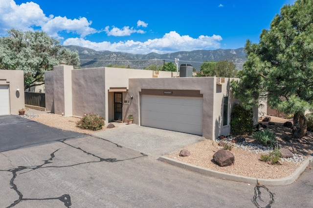 2403 Tramway Terrace Ct NE, Albuquerque, NM 87122 - pueblo-style house featuring a mountain view, a garage, central AC unit, and stucco siding