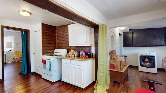 1207 Barelas Rd SW, Albuquerque, NM 87102 - kitchen featuring white gas range oven, washer / dryer, brick wall, dark wood finished floors, and white cabinets