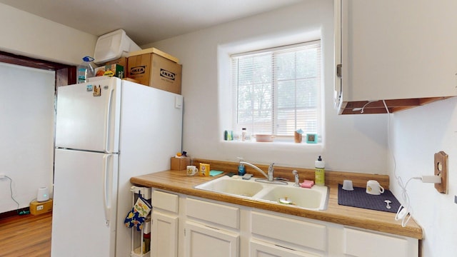 1207 Barelas Rd SW, Albuquerque, NM 87102 - kitchen with freestanding refrigerator, white cabinets, light countertops, and light wood finished floors