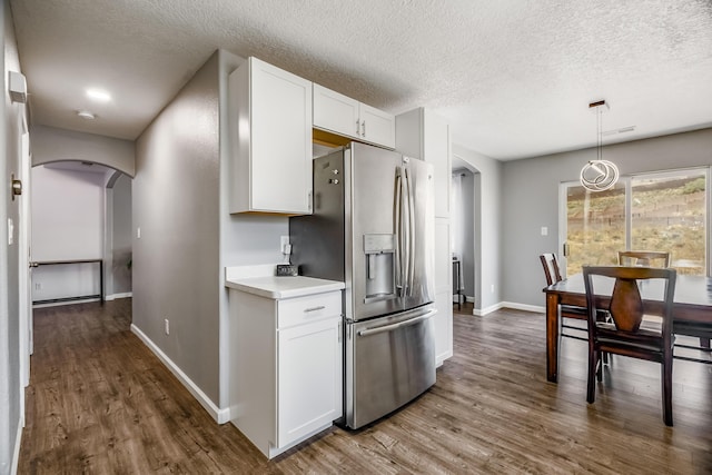 1343 San Juan Ct NE, Rio Rancho, NM 87144 - kitchen with arched walkways, stainless steel refrigerator with ice dispenser, dark wood-type flooring, white cabinets, and a textured ceiling