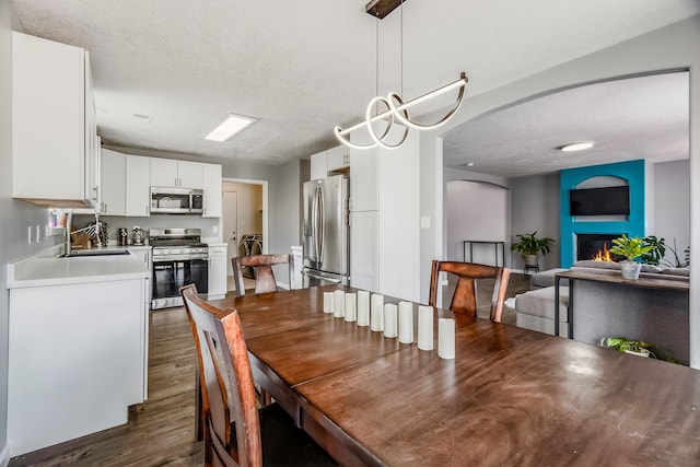 1343 San Juan Ct NE, Rio Rancho, NM 87144 - dining space with a textured ceiling, a glass covered fireplace, arched walkways, dark wood-style flooring, and washer and dryer