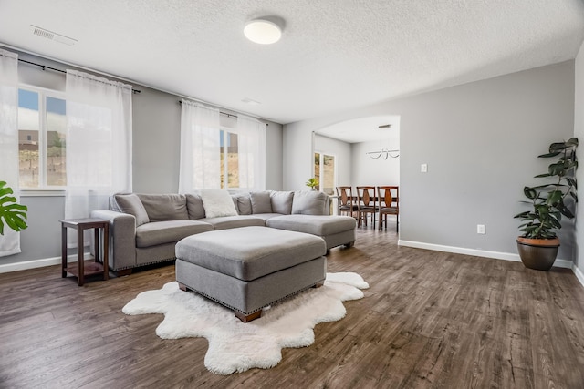 1343 San Juan Ct NE, Rio Rancho, NM 87144 - living area with dark wood-type flooring, a textured ceiling, arched walkways, and a chandelier