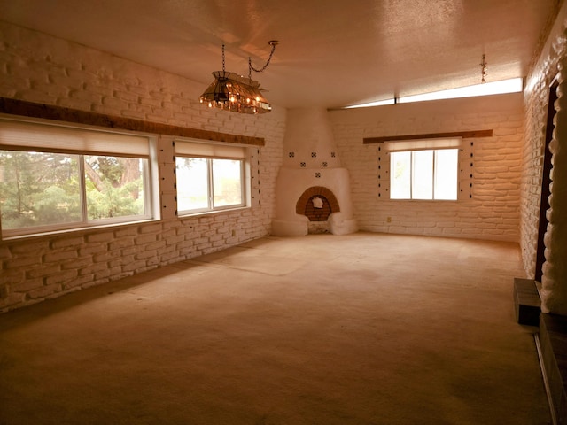 83 Paseo De San Antonio Rd, Placitas, NM 87043 - unfurnished living room with brick wall, a chandelier, carpet floors, and plenty of natural light