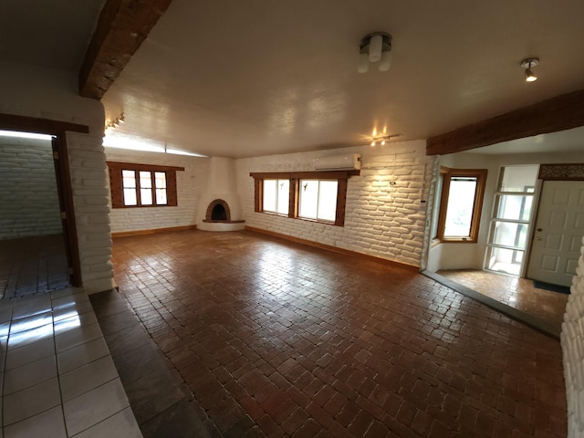 83 Paseo De San Antonio Rd, Placitas, NM 87043 - unfurnished living room featuring a fireplace, beam ceiling, brick wall, brick floors, and a wall mounted air conditioner