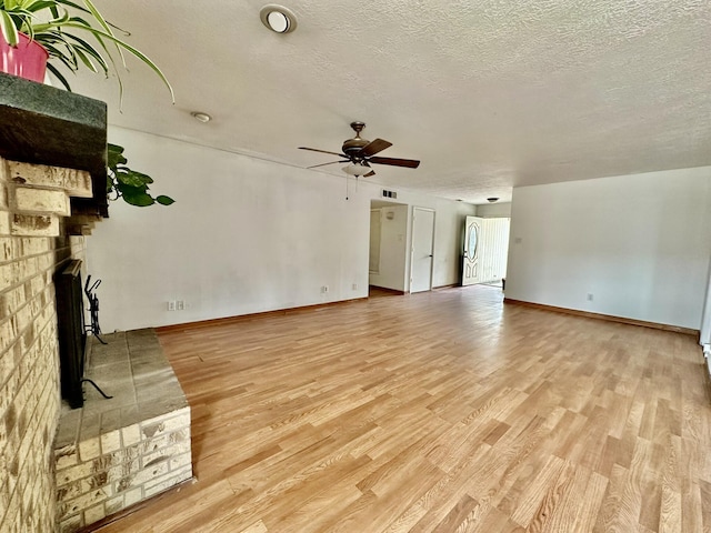 3901 70th St NW, Albuquerque, NM 87120 - unfurnished living room with light wood-type flooring, ceiling fan, a textured ceiling, a fireplace, and baseboards
