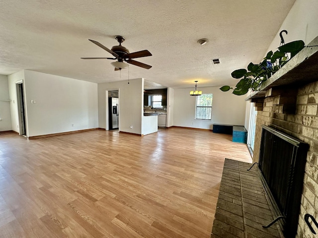3901 70th St NW, Albuquerque, NM 87120 - unfurnished living room with a brick fireplace, a ceiling fan, light wood-type flooring, a textured ceiling, and baseboards