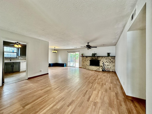 3901 70th St NW, Albuquerque, NM 87120 - unfurnished living room featuring ceiling fan, a textured ceiling, light wood finished floors, baseboards, and a brick fireplace