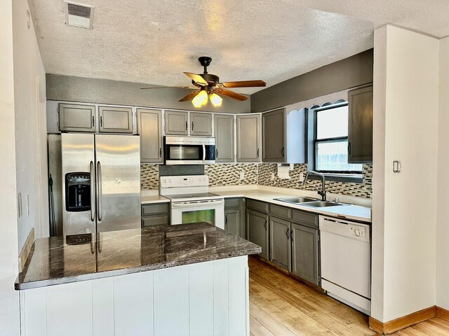 3901 70th St NW, Albuquerque, NM 87120 - kitchen featuring appliances with stainless steel finishes, a sink, light wood-style flooring, tasteful backsplash, and a textured ceiling
