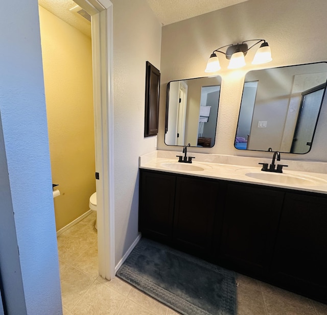 6275 Nueva Espana Rd NW, Albuquerque, NM 87114 - bathroom featuring toilet, double vanity, tile patterned floors, and a textured ceiling