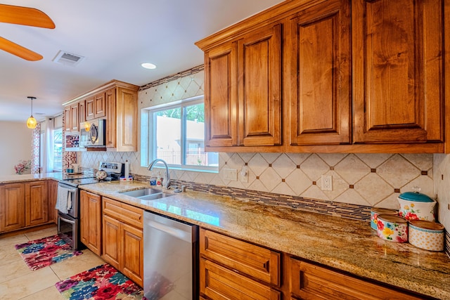 7909 Rancho De Roberto Rd NW, Albuquerque, NM 87114 - kitchen featuring stainless steel appliances, a sink, brown cabinetry, decorative backsplash, and light stone countertops