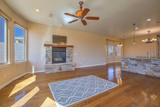 1624 23rd Ave SE, Rio Rancho, NM 87124 - living room featuring wood-type flooring, a stone fireplace, ceiling fan, baseboards, and a chandelier