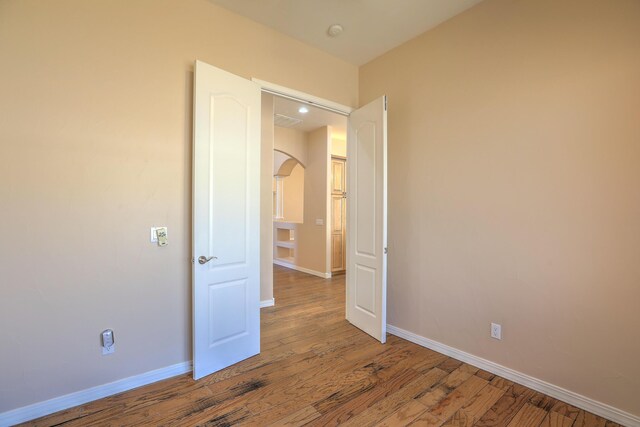 1624 23rd Ave SE, Rio Rancho, NM 87124 - unfurnished bedroom with arched walkways, baseboards, and wood finished floors