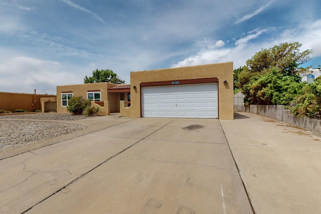 10017 Boulder St NW, Albuquerque, NM 87114 - pueblo-style home featuring stucco siding, concrete driveway, a garage, and a tile roof