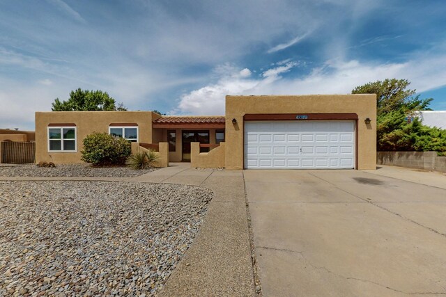 10017 Boulder St NW, Albuquerque, NM 87114 - pueblo-style home featuring stucco siding, concrete driveway, a tiled roof, and a garage