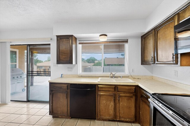 10017 Boulder St NW, Albuquerque, NM 87114 - kitchen featuring black dishwasher, light countertops, a textured ceiling, light tile patterned flooring, and stainless steel electric range oven