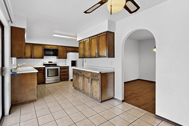 10017 Boulder St NW, Albuquerque, NM 87114 - kitchen with stainless steel range with electric stovetop, black microwave, white refrigerator with ice dispenser, ceiling fan, and light tile patterned floors