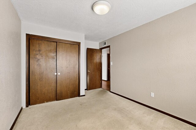 10017 Boulder St NW, Albuquerque, NM 87114 - unfurnished bedroom with a textured wall, light carpet, a closet, and a textured ceiling