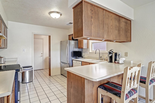 12323 Haines Ave NE, Albuquerque, NM 87112 - kitchen with a sink, appliances with stainless steel finishes, a peninsula, light countertops, and brown cabinets