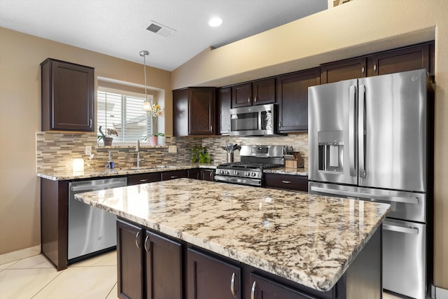 8031 Corn Mountain Pl NW, Albuquerque, NM 87114 - kitchen with stainless steel appliances, tasteful backsplash, vaulted ceiling, dark brown cabinets, and light stone countertops
