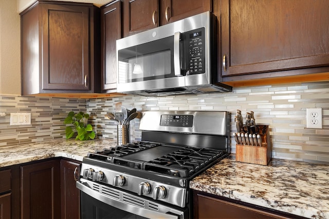 8031 Corn Mountain Pl NW, Albuquerque, NM 87114 - kitchen with appliances with stainless steel finishes, tasteful backsplash, light stone counters, and dark brown cabinetry