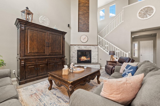 4118 Pico Norte Ln NE, Rio Rancho, NM 87124 - living room featuring a towering ceiling, stairway, light wood-style floors, a brick fireplace, and healthy amount of natural light