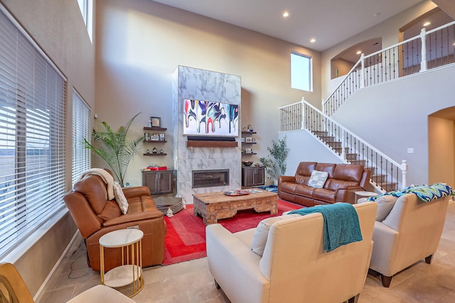 2350 Sandra Loop NE, Rio Rancho, NM 87144 - living room featuring a high ceiling, a tiled fireplace, stairs, arched walkways, and recessed lighting
