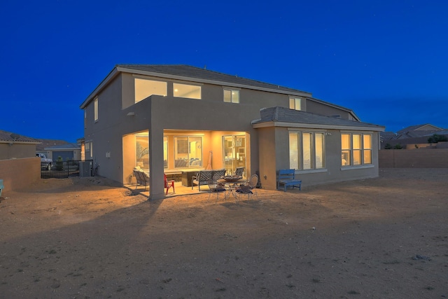 2350 Sandra Loop NE, Rio Rancho, NM 87144 - back of house at twilight with stucco siding, cooling unit, and a patio