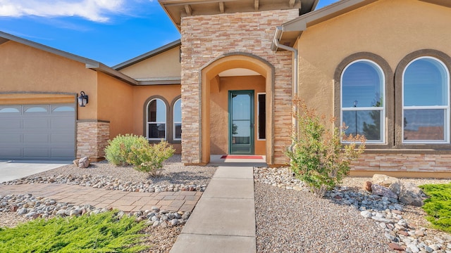4281 Palo Verde Ct, Los Lunas, NM 87031 - doorway to property featuring stucco siding, an attached garage, stone siding, and driveway