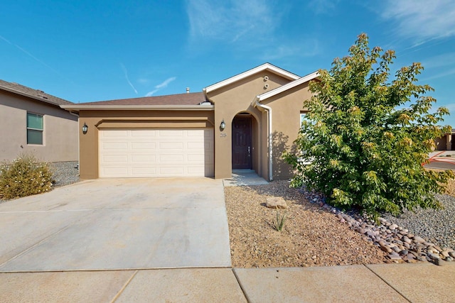 215 Adeline Ave, Los Lunas, NM 87031 - view of front of home with stucco siding, driveway, and an attached garage