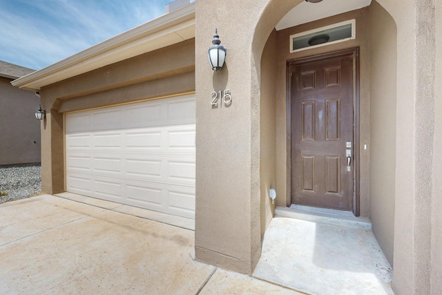 215 Adeline Ave, Los Lunas, NM 87031 - view of exterior entry featuring stucco siding, driveway, and a garage