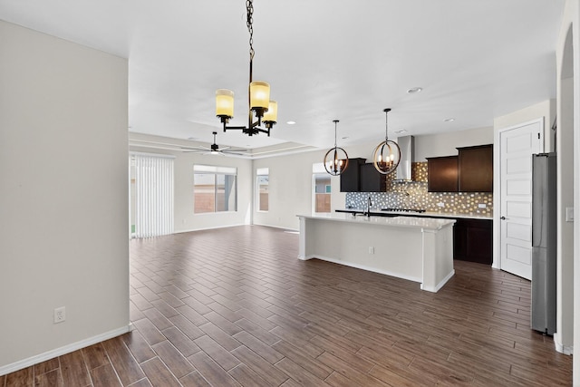 275 Adeline Ave, Los Lunas, NM 87031 - kitchen featuring a chandelier, wall chimney exhaust hood, a ceiling fan, light countertops, and decorative backsplash
