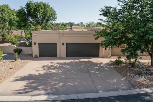 317 Plaza Muchomas, Bernalillo, NM 87004 - pueblo revival-style home featuring an attached garage, concrete driveway, and stucco siding