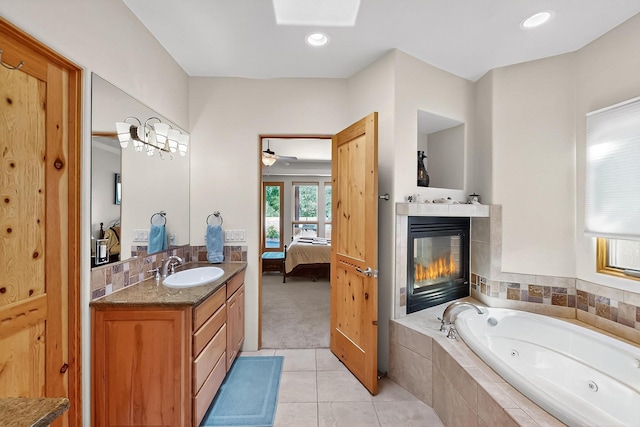 317 Plaza Muchomas, Bernalillo, NM 87004 - bathroom featuring connected bathroom, a tub with jets, vanity, tile patterned flooring, and a fireplace