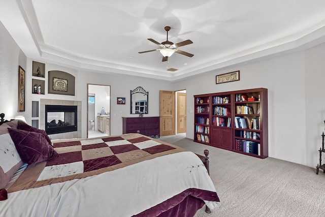 317 Plaza Muchomas, Bernalillo, NM 87004 - bedroom featuring carpet floors, a tray ceiling, a fireplace, connected bathroom, and ceiling fan