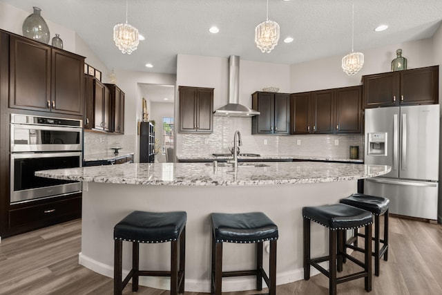 9128 Vista Bosquejo Rd NW, Albuquerque, NM 87120 - kitchen featuring stainless steel appliances, wall chimney range hood, a chandelier, dark brown cabinetry, and recessed lighting