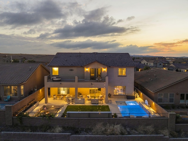 9128 Vista Bosquejo Rd NW, Albuquerque, NM 87120 - back of property at dusk with a balcony, outdoor lounge area, an in-ground hot tub, stucco siding, and a fenced backyard