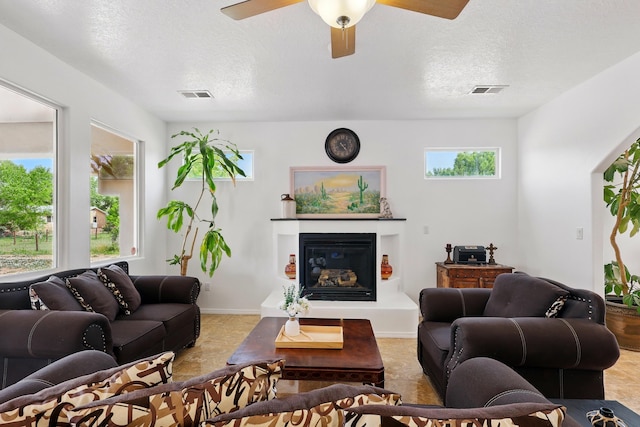 2061 Blaylock Ln NE, Los Lunas, NM 87031 - living area with a glass covered fireplace, a textured ceiling, and ceiling fan