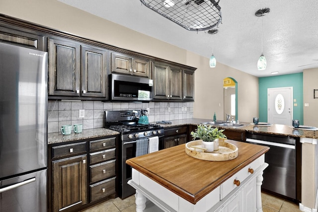 805 Palo Duro Dr, Bernalillo, NM 87004 - kitchen with appliances with stainless steel finishes, dark brown cabinetry, light tile patterned flooring, and a textured ceiling