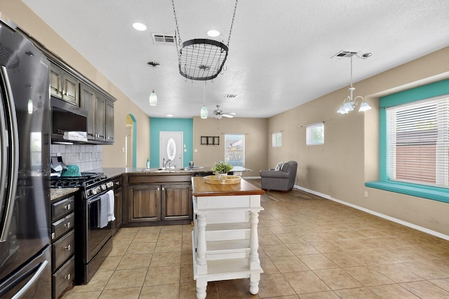805 Palo Duro Dr, Bernalillo, NM 87004 - kitchen featuring appliances with stainless steel finishes, a chandelier, decorative backsplash, a peninsula, and light tile patterned floors