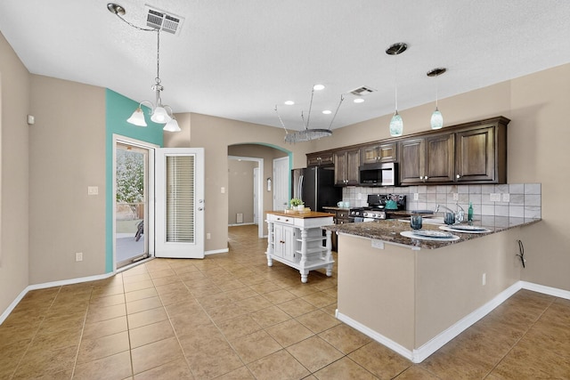 805 Palo Duro Dr, Bernalillo, NM 87004 - kitchen featuring appliances with stainless steel finishes, decorative backsplash, arched walkways, dark brown cabinetry, and light tile patterned flooring