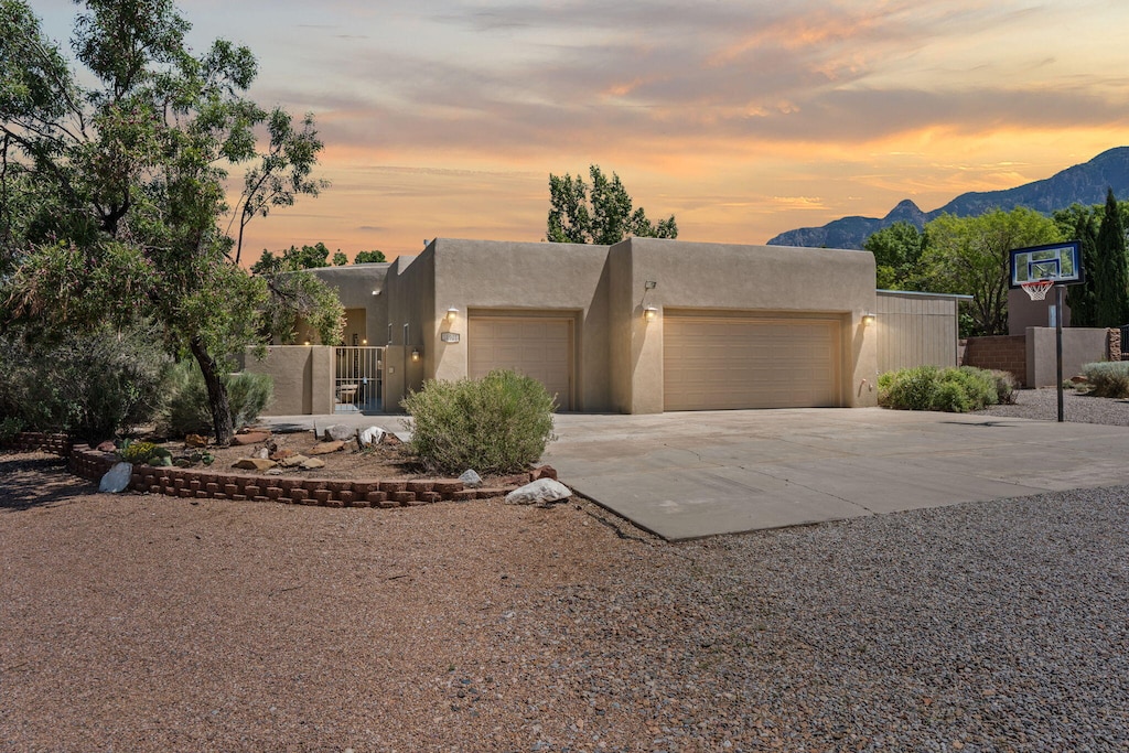 11901 Eagle Rock Ave NE, Albuquerque, NM 87122 - pueblo revival-style home featuring a garage, concrete driveway, stucco siding, and a mountain view